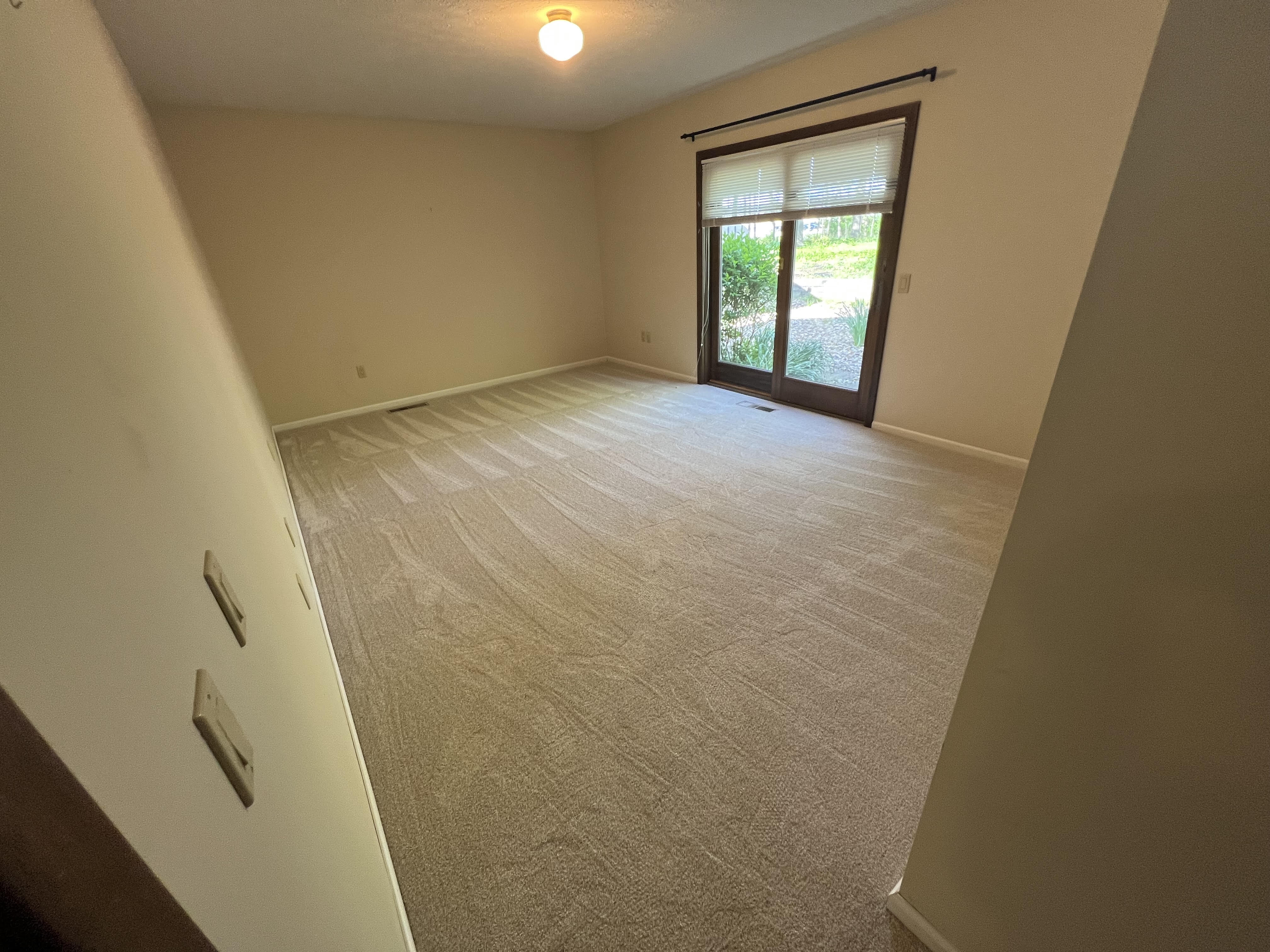 Plush beige carpet in a bright Strongsville bedroom with a sliding door to the backyard